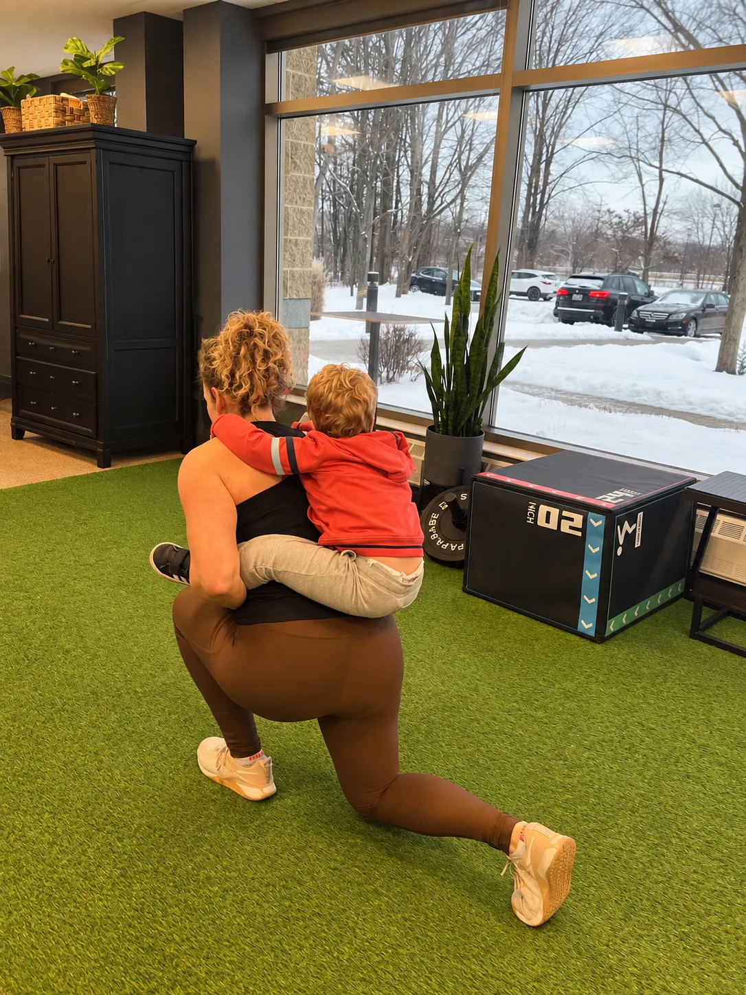An active parent doing a lunge while holding her child at the Bridge clinic